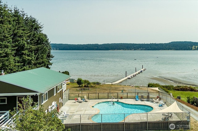 community pool with a patio, a water view, and fence