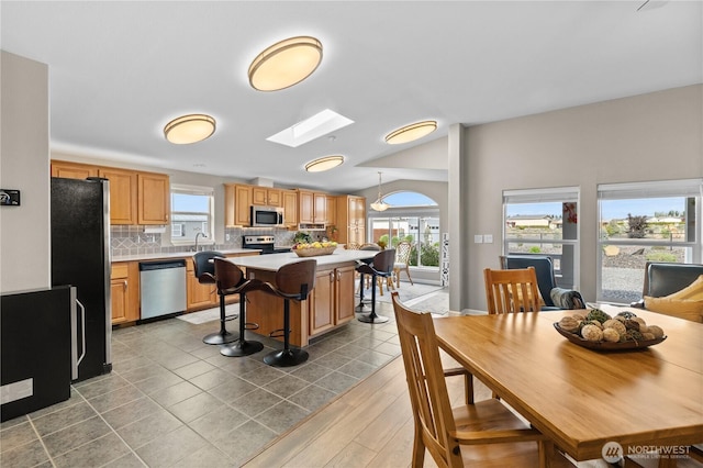 kitchen with appliances with stainless steel finishes, light countertops, a kitchen island, backsplash, and a kitchen breakfast bar