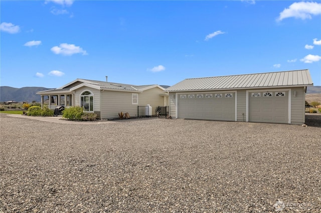 ranch-style home featuring metal roof, a mountain view, and driveway