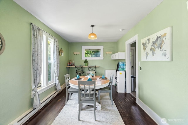 dining room with a baseboard heating unit, dark wood-style floors, washing machine and dryer, and baseboards