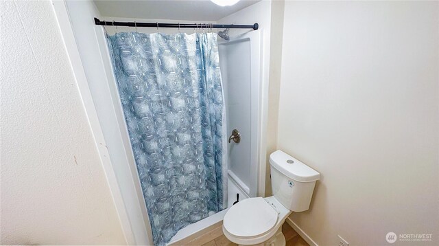bathroom featuring a shower with curtain and toilet