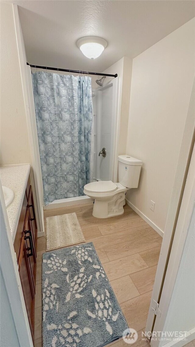 full bathroom with wood finished floors, vanity, baseboards, toilet, and a shower with shower curtain