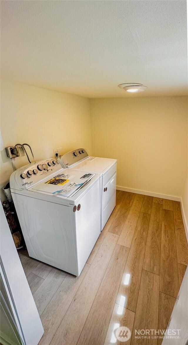 laundry area with light wood-style floors, baseboards, laundry area, and washer and clothes dryer