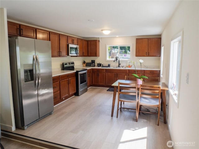 kitchen featuring light countertops, appliances with stainless steel finishes, and brown cabinetry