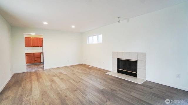 unfurnished living room featuring a fireplace, recessed lighting, baseboards, and light wood-type flooring