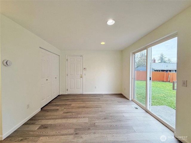 empty room featuring wood finished floors, recessed lighting, visible vents, and baseboards