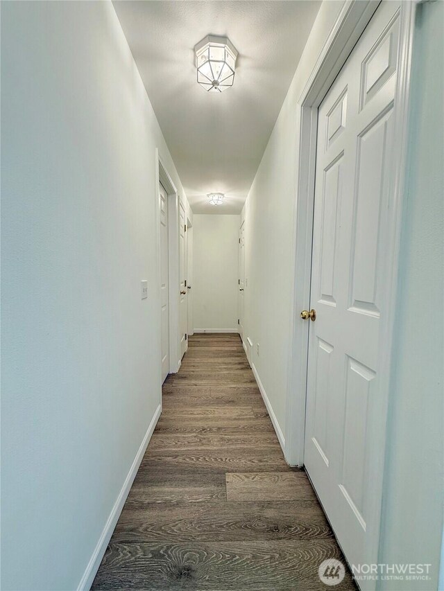 corridor with baseboards and wood finished floors