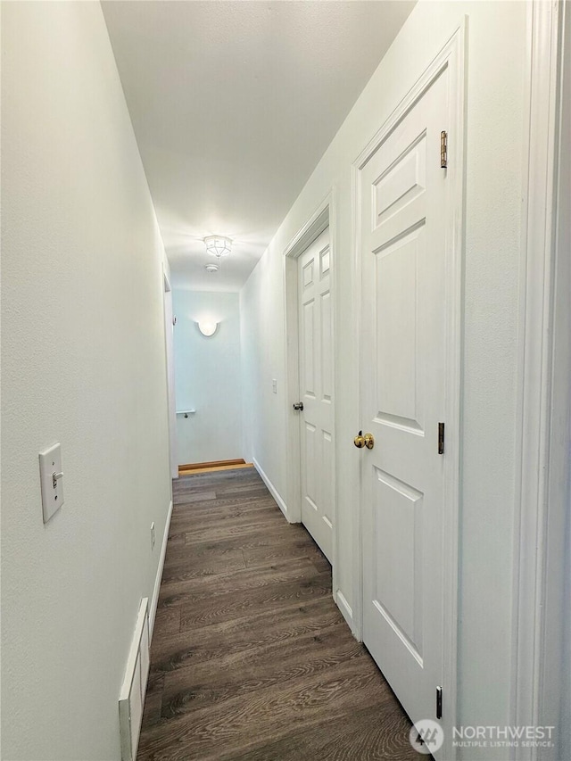 hall with visible vents, dark wood-style flooring, and baseboards