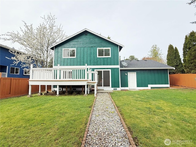 view of front of property with a front lawn, board and batten siding, a wooden deck, and a fenced backyard