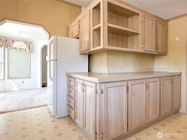 kitchen with freestanding refrigerator, light brown cabinets, light countertops, arched walkways, and open shelves