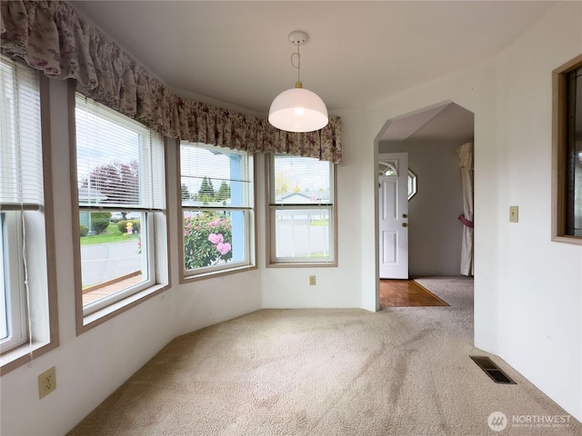 unfurnished dining area featuring carpet floors and arched walkways