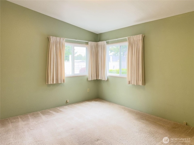carpeted spare room with lofted ceiling