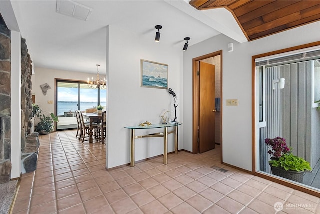 hall featuring light tile patterned floors, baseboards, a chandelier, and visible vents