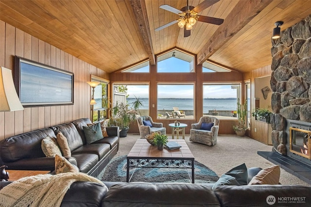 carpeted living room with a water view, wood walls, lofted ceiling with beams, and wooden ceiling