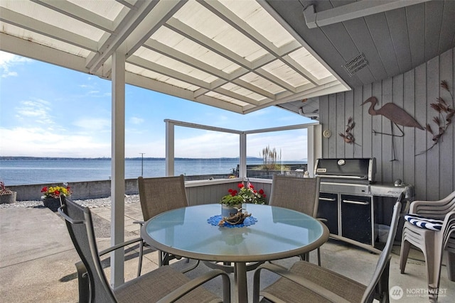 view of patio with a water view, outdoor dining space, visible vents, and a grill
