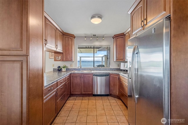 kitchen featuring a sink, appliances with stainless steel finishes, brown cabinetry, and light tile patterned flooring