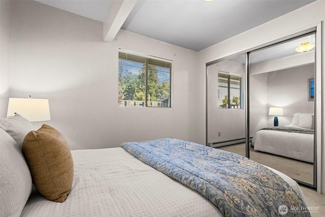 carpeted bedroom featuring a closet, a baseboard heating unit, and beam ceiling