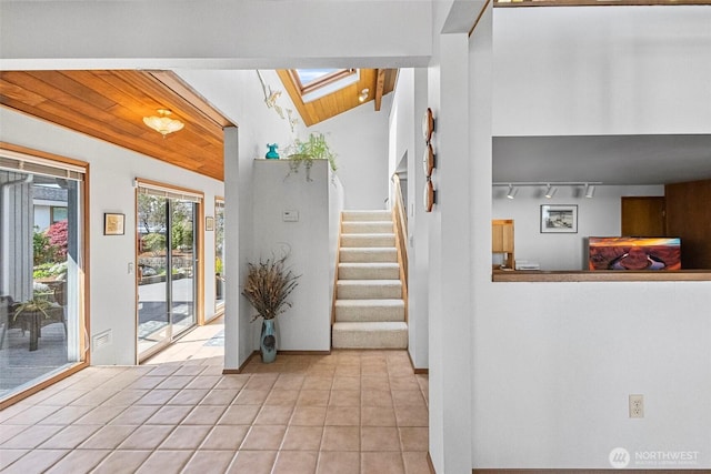 tiled foyer entrance with track lighting, wood ceiling, a skylight, and stairway
