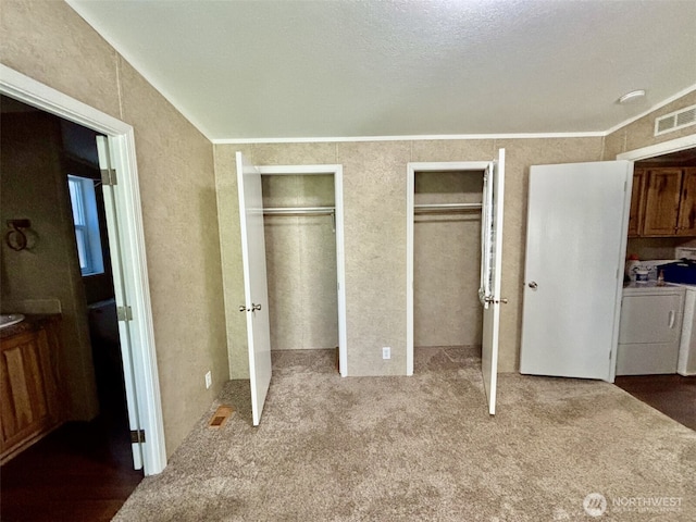 unfurnished bedroom featuring two closets, independent washer and dryer, carpet flooring, and visible vents