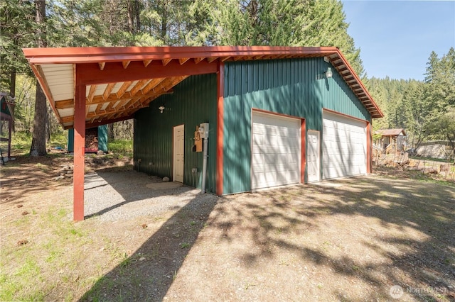 exterior space featuring an outdoor structure, driveway, and a forest view