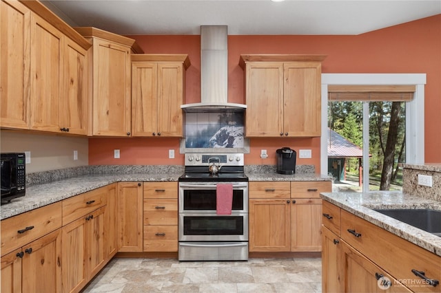 kitchen featuring black microwave, light brown cabinetry, wall chimney exhaust hood, and range with two ovens