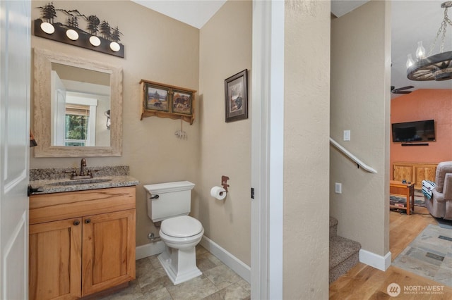 bathroom featuring toilet, baseboards, ceiling fan, and vanity