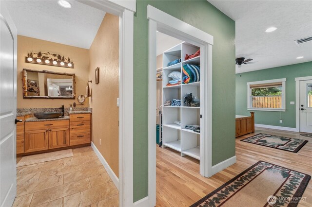 hall featuring visible vents, a sink, baseboards, and recessed lighting