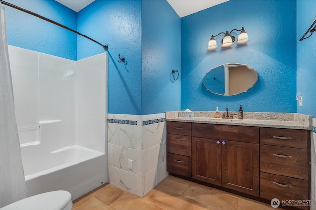 bathroom with tile patterned flooring, vanity, toilet, a textured wall, and shower / bath combo with shower curtain