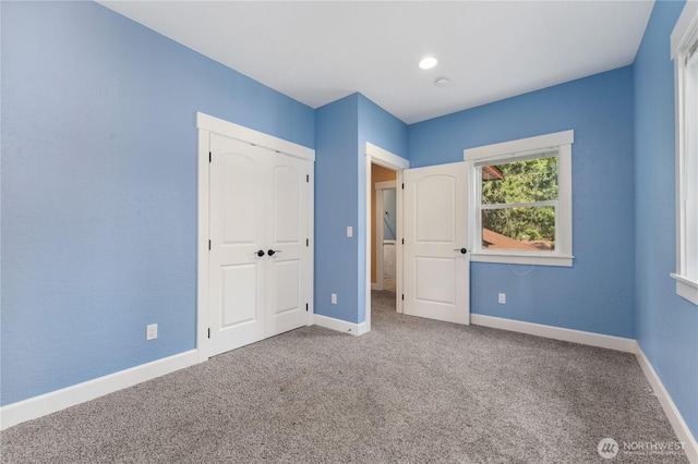 unfurnished bedroom with baseboards, carpet, and a closet
