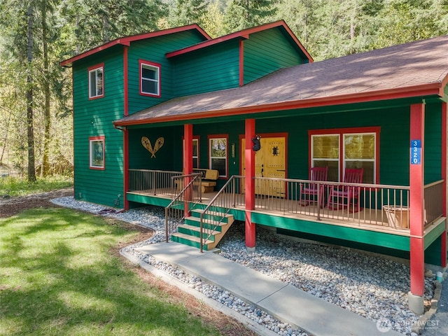 rustic home with roof with shingles, a porch, and a front lawn