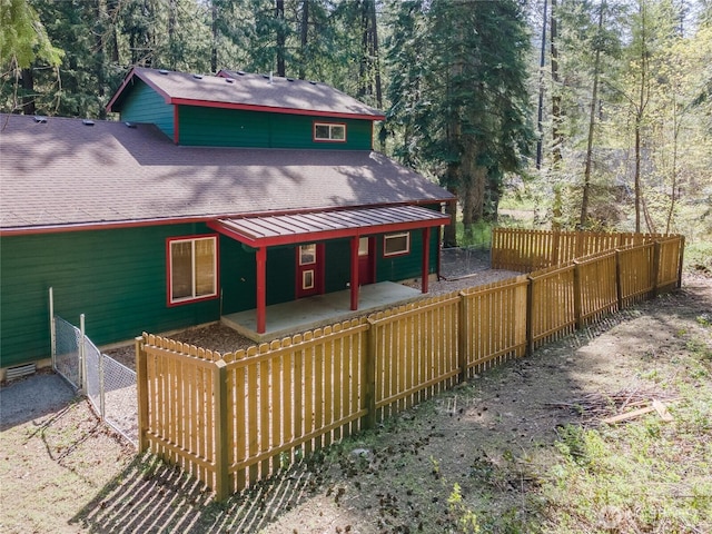 back of property with fence private yard, roof with shingles, and a patio area