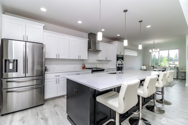 6318 230th Avenue Ct E, Buckley, WA 98321 - kitchen featuring a sink, a kitchen island with sink, backsplash, wall chimney exhaust hood, and appliances with stainless steel finishes