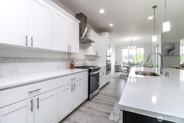 6318 230th Avenue Ct E, Buckley, WA 98321 - kitchen with wall chimney exhaust hood, a sink, range with gas cooktop, a notable chandelier, and white cabinetry