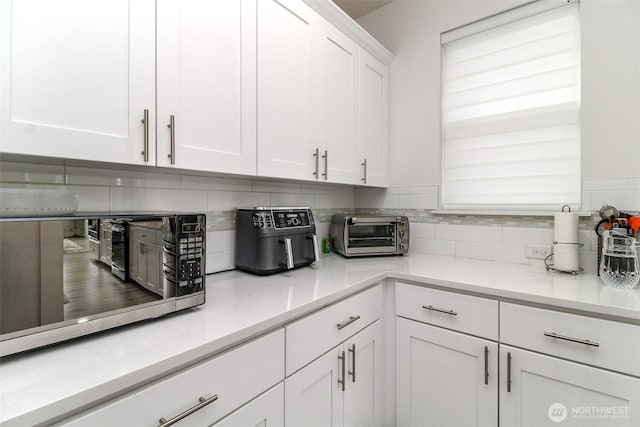 6318 230th Avenue Ct E, Buckley, WA 98321 - kitchen featuring white cabinets, a toaster, light countertops, stainless steel microwave, and decorative backsplash