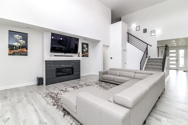 6318 230th Avenue Ct E, Buckley, WA 98321 - living area featuring wood finished floors, a tile fireplace, a towering ceiling, and stairway