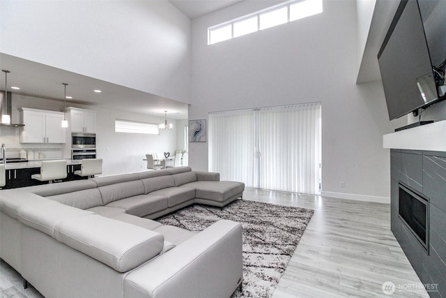 6318 230th Avenue Ct E, Buckley, WA 98321 - living area with a glass covered fireplace, light wood finished floors, baseboards, a high ceiling, and recessed lighting
