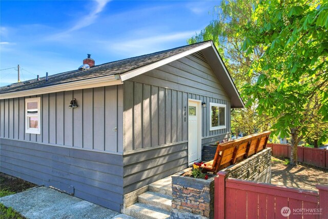 240 Willow St, Bremerton, WA 98310 - view of home's exterior with board and batten siding, roof with shingles, a chimney, and fence