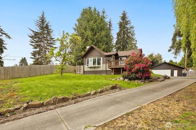 view of front facade featuring a front yard, a deck, a detached garage, fence, and an outdoor structure