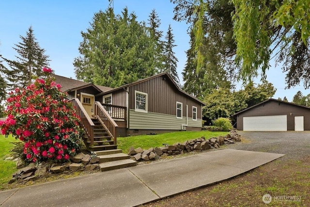 view of front facade with a garage, a wooden deck, stairs, crawl space, and an outbuilding
