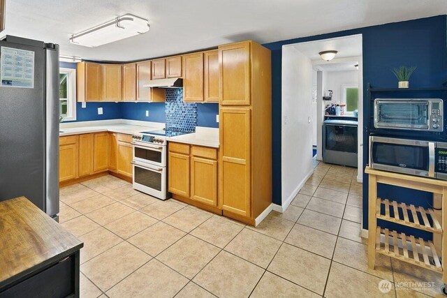 kitchen featuring light countertops, stainless steel appliances, light tile patterned floors, a toaster, and under cabinet range hood