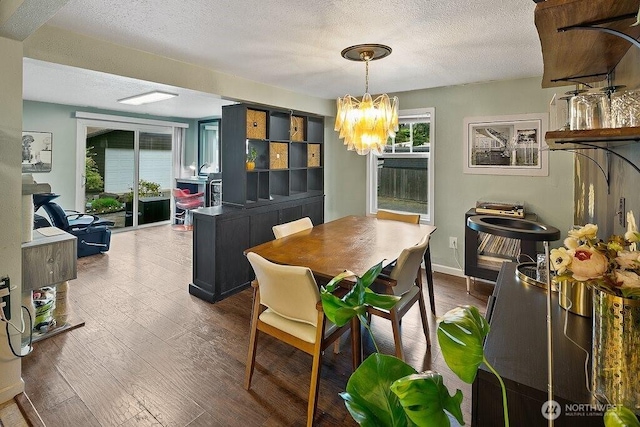 dining area with a textured ceiling, a chandelier, and wood finished floors