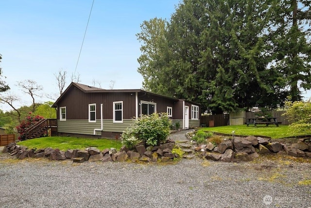 view of front of house featuring fence, stairs, and a front yard