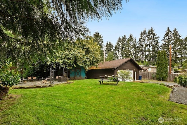 view of yard with a storage shed, fence, an outbuilding, and a garage