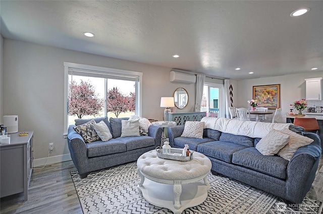 living room featuring recessed lighting, a wall unit AC, and light wood-type flooring