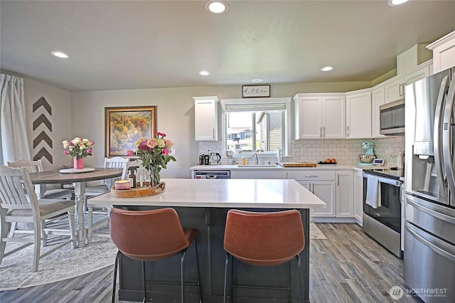 kitchen featuring recessed lighting, appliances with stainless steel finishes, wood finished floors, and a kitchen island