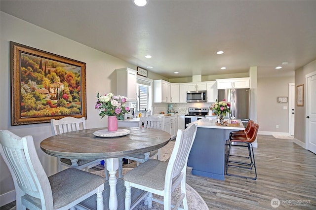 dining area featuring baseboards, light wood-type flooring, and recessed lighting