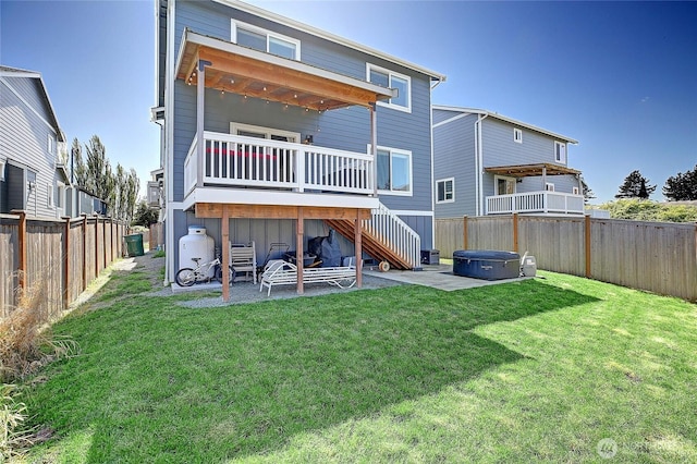 back of property with a fenced backyard, stairway, a hot tub, a patio area, and a lawn