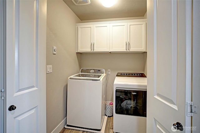 washroom with washer and dryer, cabinet space, wood finished floors, and baseboards