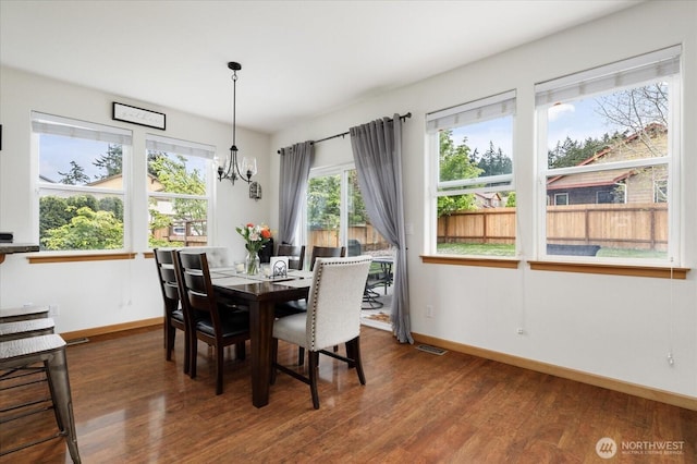 dining area featuring a chandelier, baseboards, visible vents, and wood finished floors
