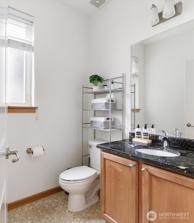 bathroom with vanity, baseboards, visible vents, and toilet